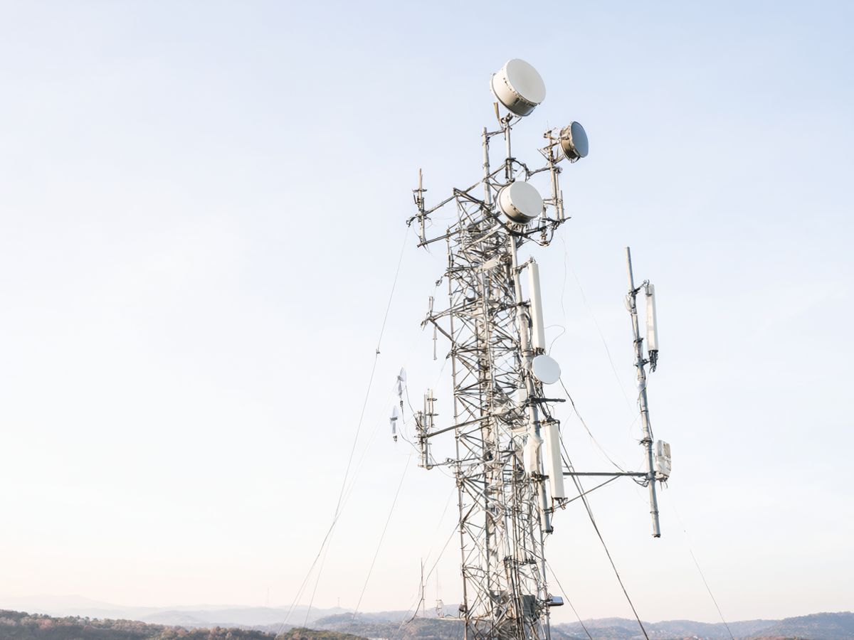 Lattice tower with microwave backhaul dishes at dusk