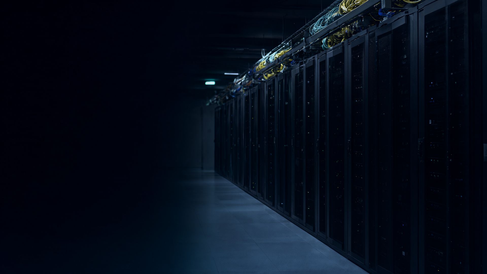Data-centre corridor lined with racks and bundles of fibre in cool blue light