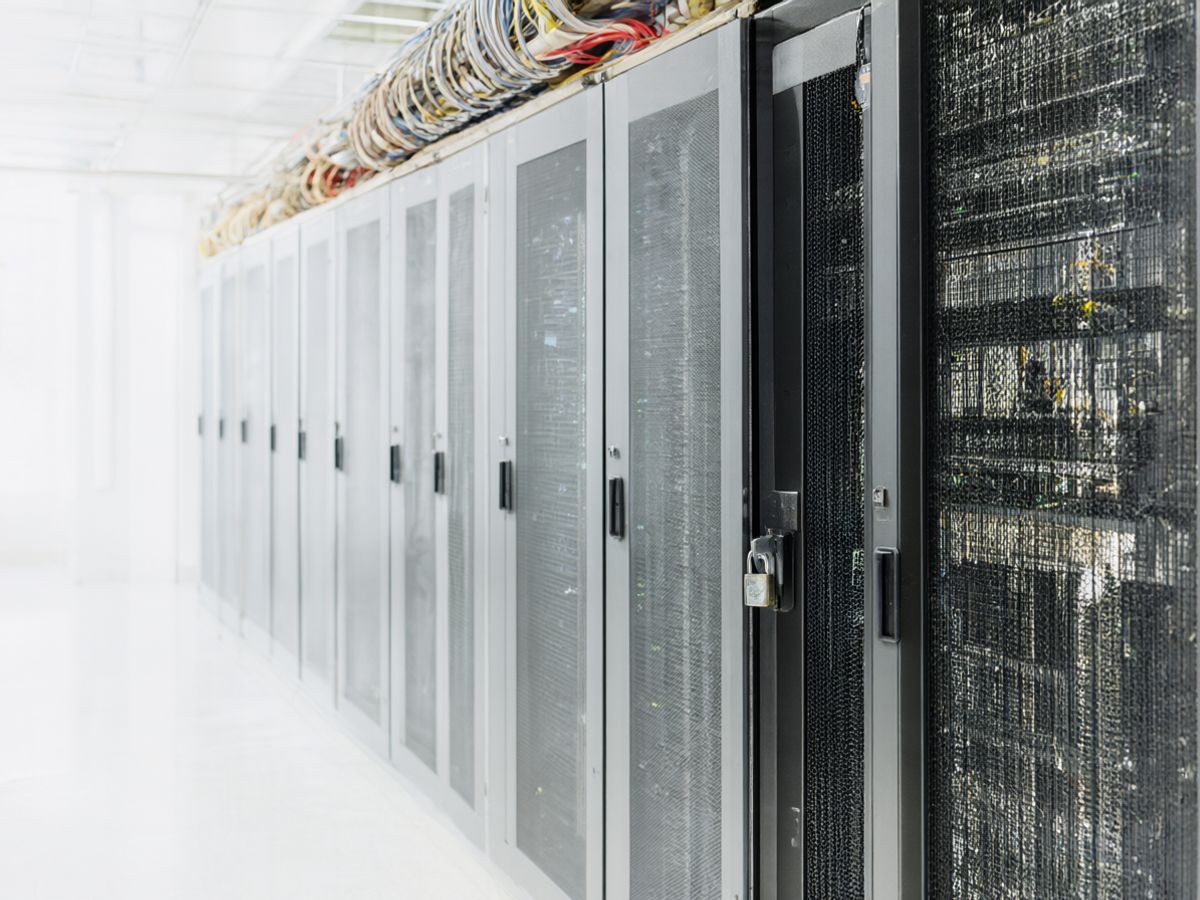 Locked racks in a data centre behind a mesh cage door with a padlock